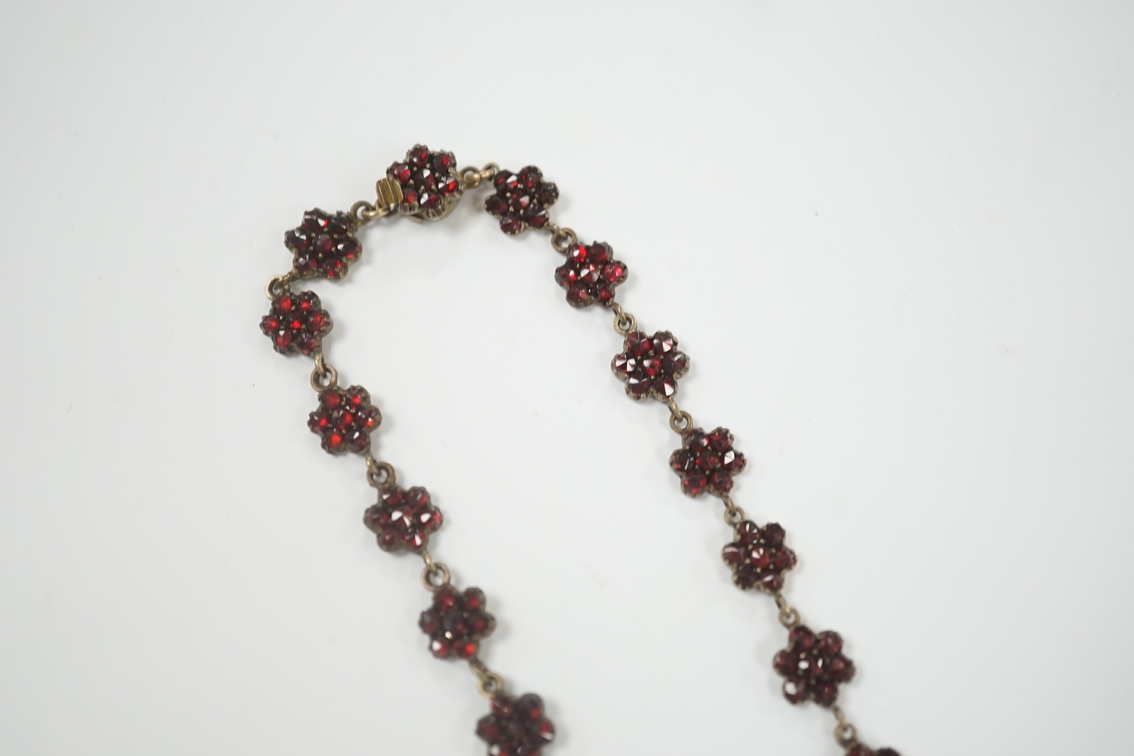 A Victorian gilt metal and facet cut garnet cluster set mourning drop pendant necklace, overall 50cm.